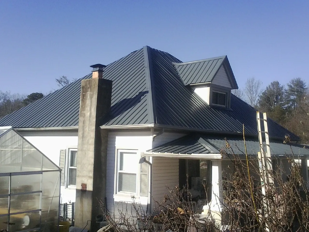 Dark blue standing seam metal roof on a white farmhouse with dormer — Slate & Tile Roof Repair by Roofing Brothers in Big Clifty