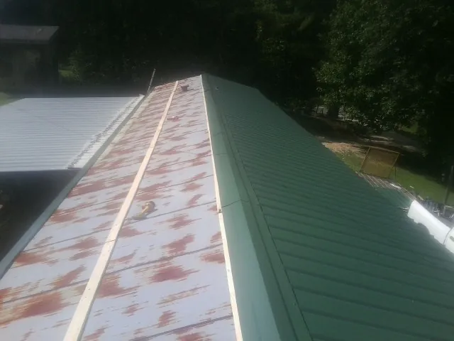 Old rusted panels beside newly installed green metal roofing — Wind Damage Roof Repair by Roofing Brothers in Big Clifty