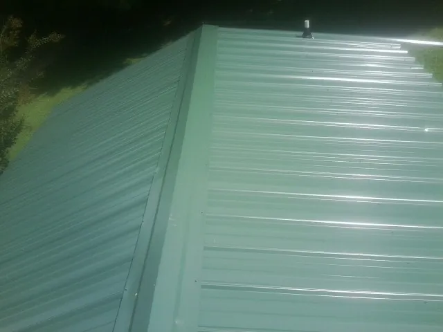 New green metal panels meeting at the ridge of a roof — Flat Roof Repair work by our crew in Big Clifty