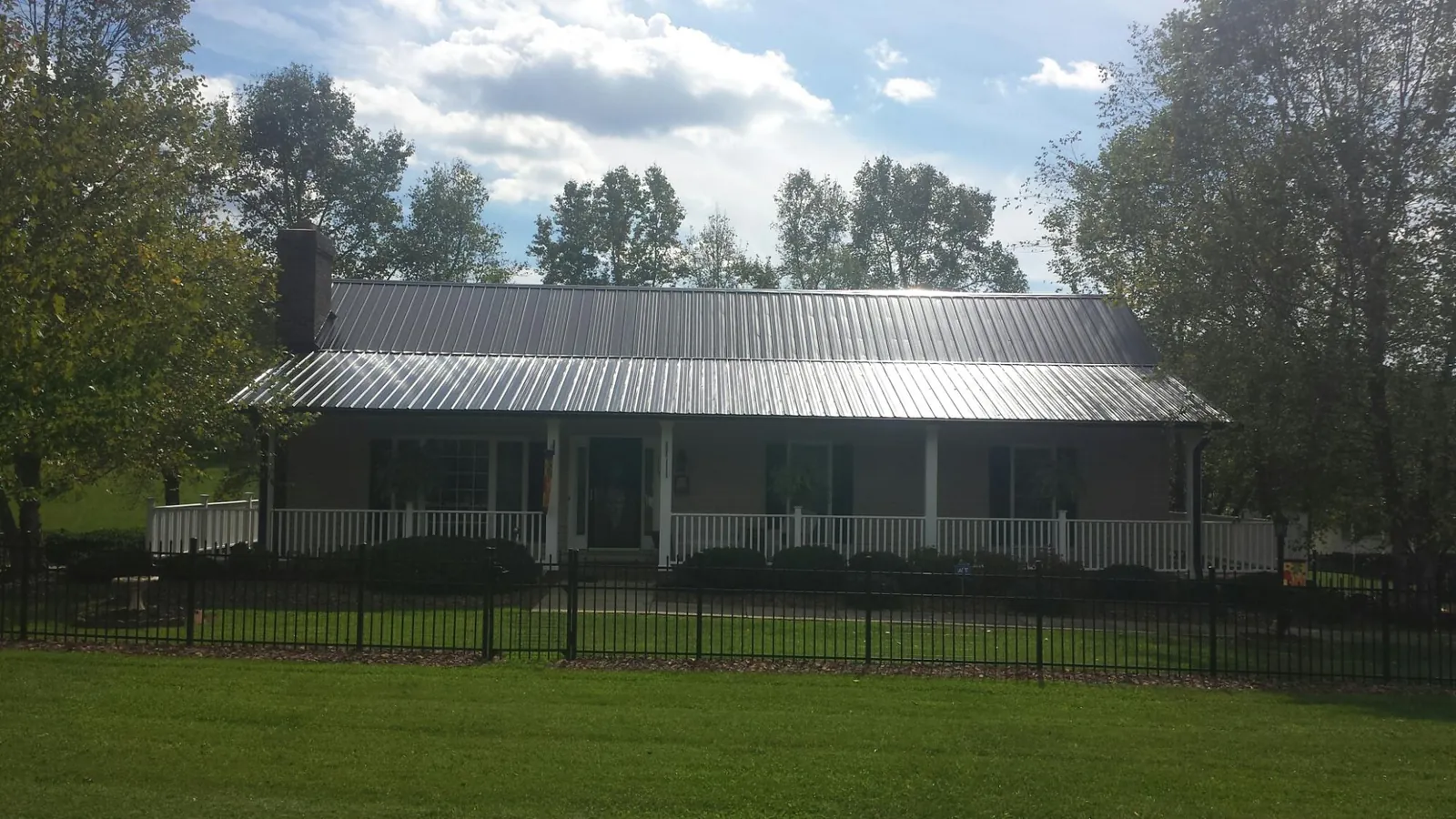 Gray metal roof on a brick ranch with a full width front porch — Gutter Guard Installation work by our crew in Big Clifty