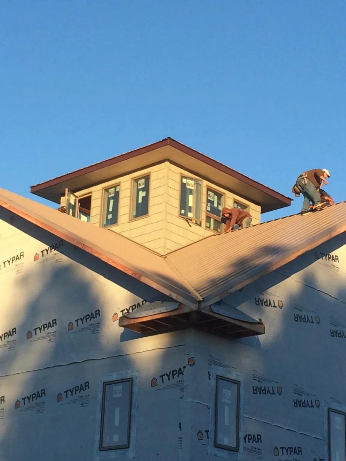 Roofers working around a rooftop cupola on a new metal roof at sunset — Roof Waterproofing in Big Clifty by Roofing Brothers